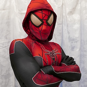 Puede incluir: Una persona que lleva un traje de Spiderman rojo y negro con una m&aacute;scara con capucha negra. El traje tiene un dise&ntilde;o de telara&ntilde;a en el pecho y los brazos.