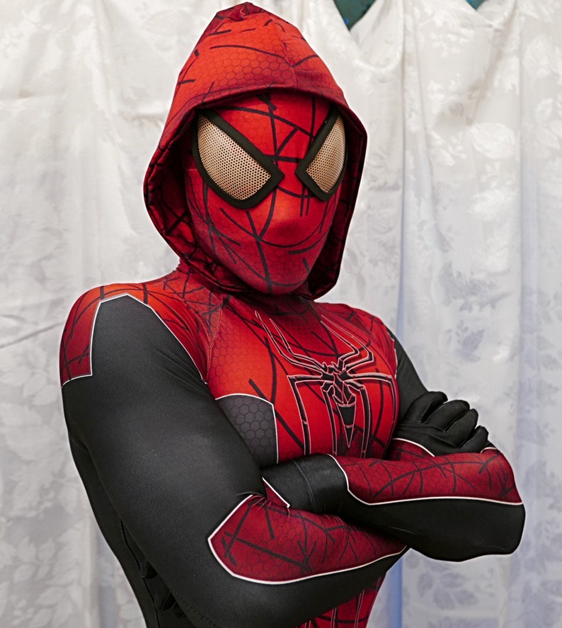 Puede incluir: Una persona que lleva un traje de Spiderman rojo y negro con una m&aacute;scara con capucha negra. El traje tiene un dise&ntilde;o de telara&ntilde;a en el pecho y los brazos.