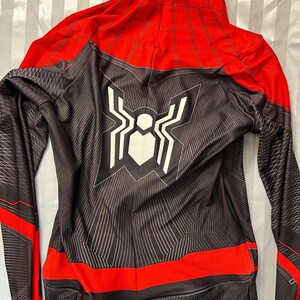 May include: Black and red Spiderman costume with a white spider logo on the back. The costume has a zip in the front and a hood.