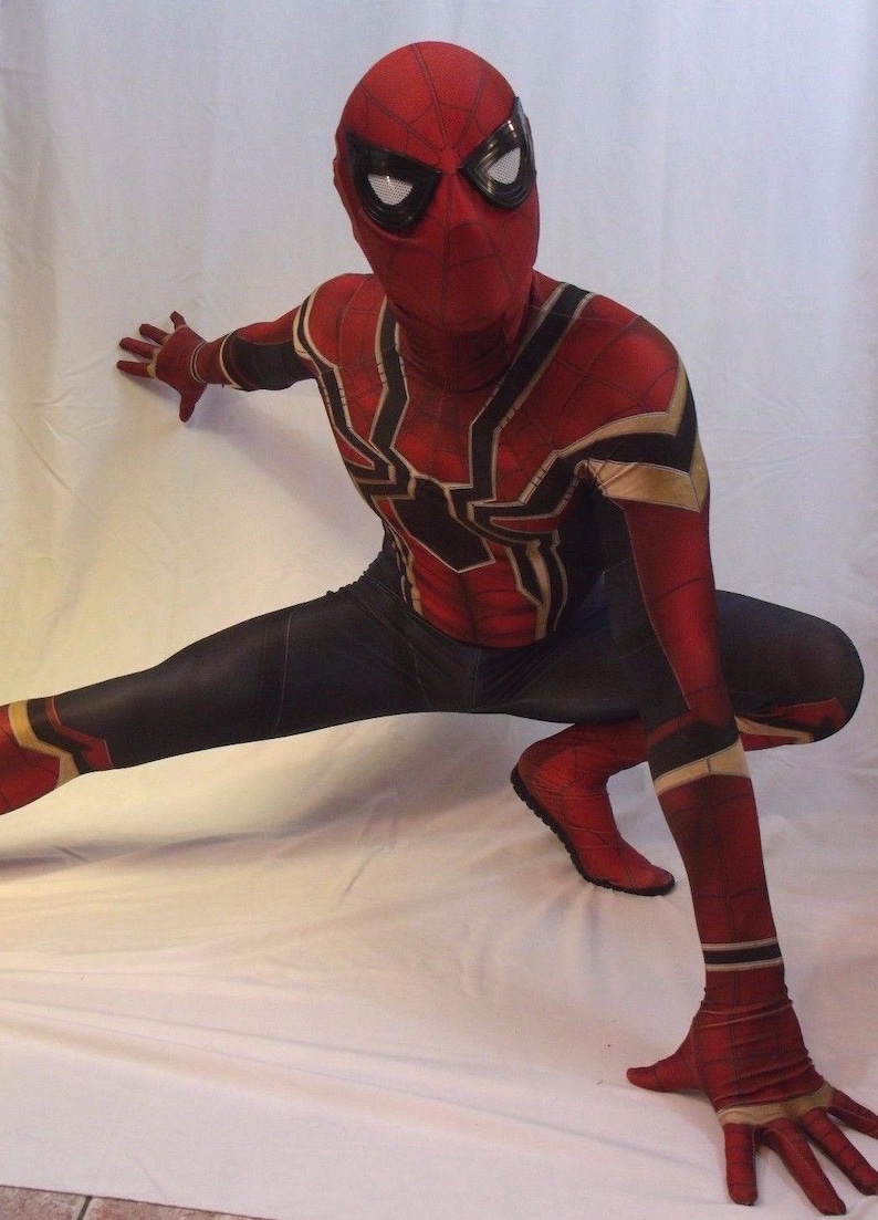 May include: A red and black spandex superhero costume with a spider design. The costume has a mask with black eye holes and a white spider design.