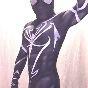 Może przedstawiać: Czarno-biały kostium z spandexu z wzorem pajęczyny. Kostium ma czarną maskę z białymi oczami.