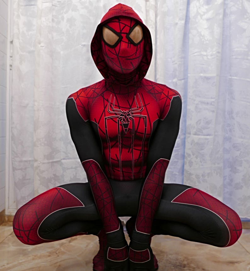 Puede incluir: Un traje de superh&eacute;roe de spandex rojo y negro con un dise&ntilde;o de telara&ntilde;a. El traje incluye una m&aacute;scara con capucha con un dise&ntilde;o de telara&ntilde;a y un logotipo de ara&ntilde;a rojo y negro en el pecho.