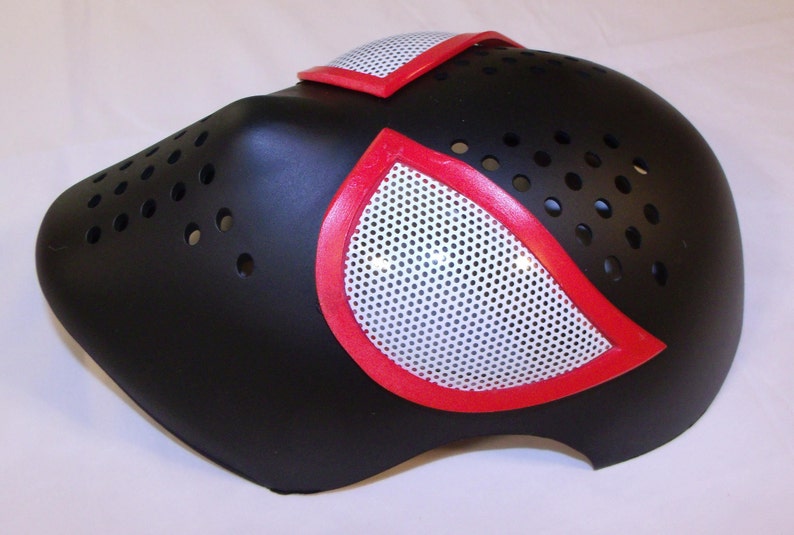 May include: Black plastic mask with red and white spider-man inspired design. The mask has a mesh covering the eyes and a series of small holes around the nose and mouth.