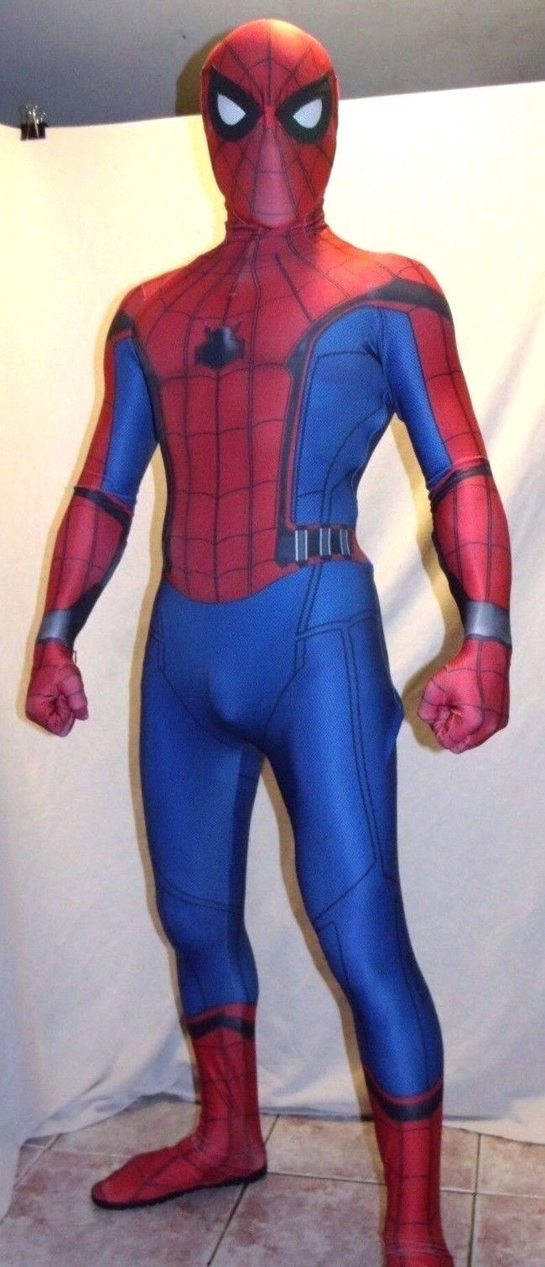 May include: A red and blue spandex costume of Spider-Man with a black spider logo on the chest. The costume has a red mask with black eyes and a web design.