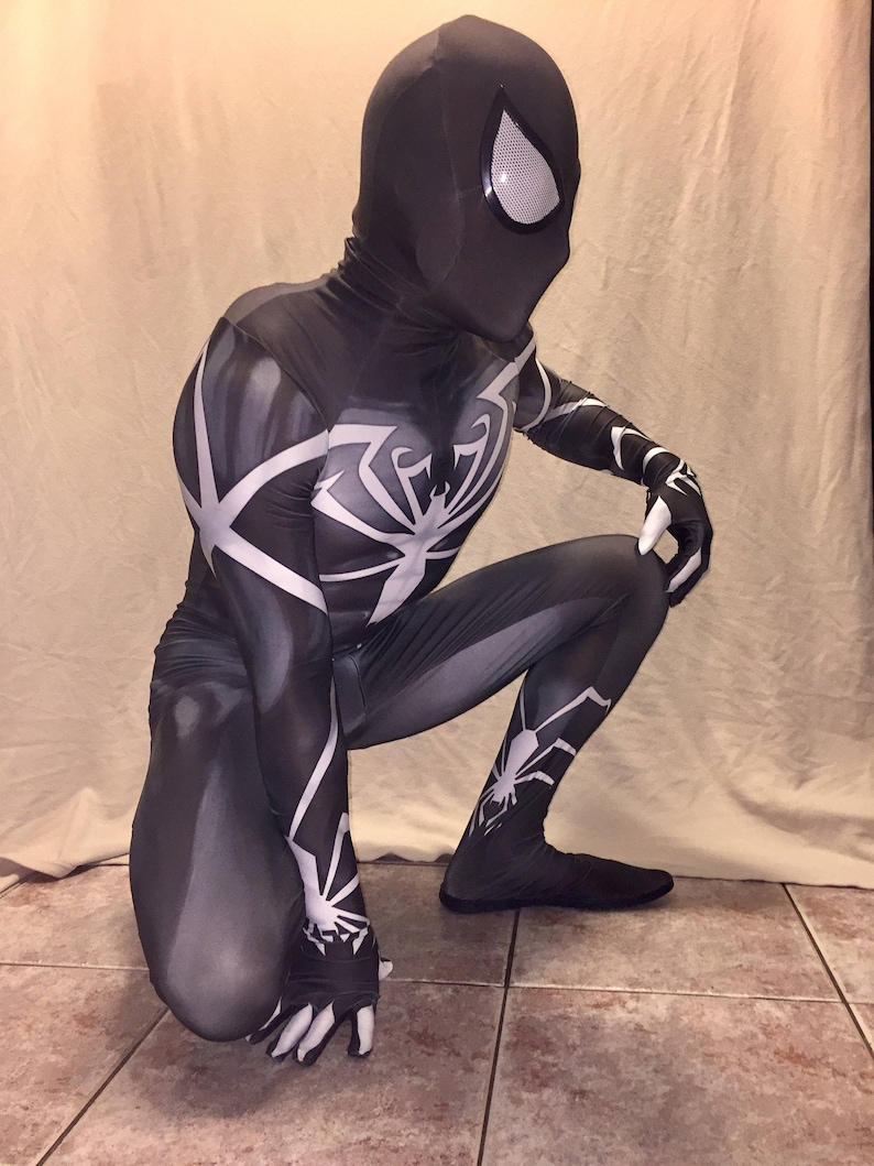Może przedstawiać: Czarno-biały kostium z spandexu z wzorem pająka. Kostium ma czarną maskę z białym wzorem oka.