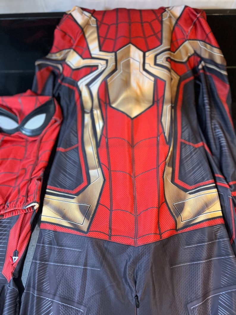 May include: A red and black Spiderman costume with a gold spider symbol on the chest. The costume has a zipper at the back.