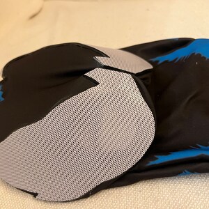 Puede incluir: Rodillera negra y azul con un panel de malla gris. La rodillera est&aacute; hecha de un material suave y transpirable y est&aacute; dise&ntilde;ada para brindar soporte y protecci&oacute;n.