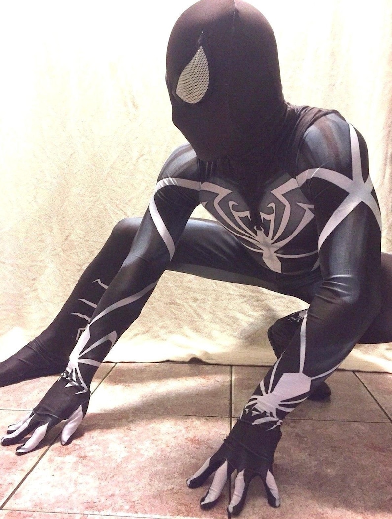 Może przedstawiać: Czarno-biały kostium ze spandexu z wzorem pająka. Kostium ma czarną maskę z białym wzorem oka.