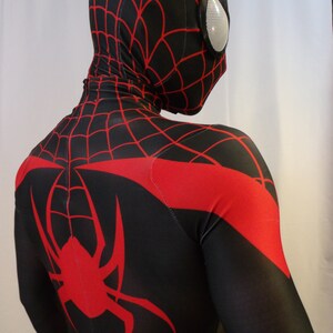 May include: A black and red spandex suit with a spider design on the back. The suit has a red spider web pattern on the chest and a black mask with a red spider web pattern.