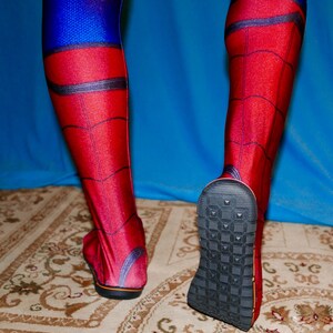 May include: A pair of red and blue spandex leggings with a spider web pattern. The leggings have black accents and a textured black sole.