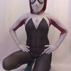 Puede incluir: Un traje de spandex blanco y rojo con un dise&ntilde;o de telara&ntilde;a negra. El traje incluye una m&aacute;scara blanca con capucha, agujeros negros para los ojos y un dise&ntilde;o de ara&ntilde;a blanca.