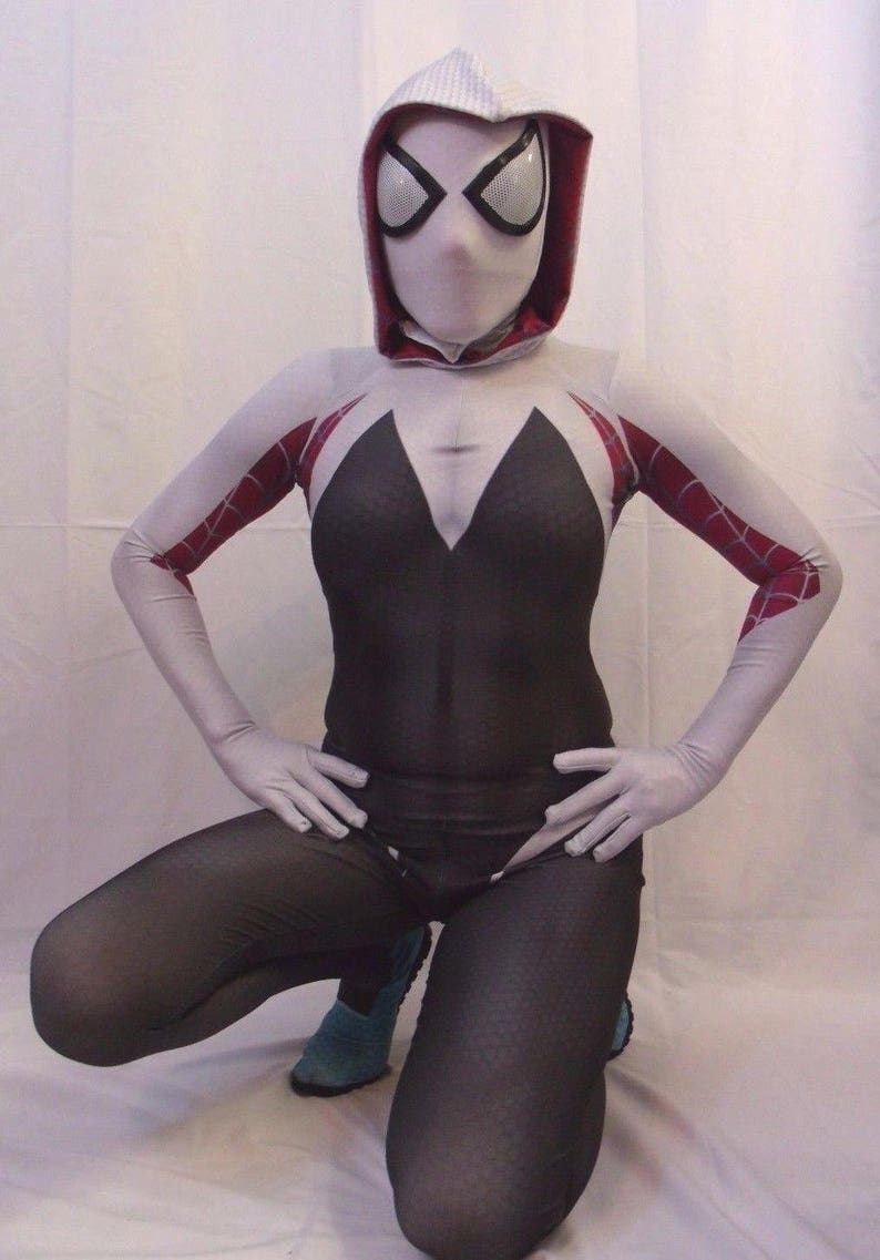 Puede incluir: Un traje de spandex blanco y rojo con un dise&ntilde;o de telara&ntilde;a negra. El traje incluye una m&aacute;scara blanca con capucha, agujeros negros para los ojos y un dise&ntilde;o de ara&ntilde;a blanca.