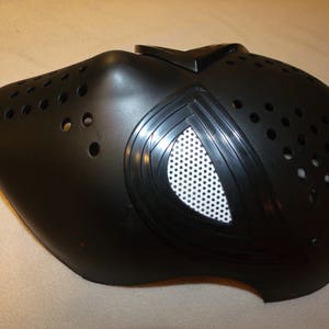 May include: Black plastic mask with a white mesh eye piece and a series of small holes throughout the mask.