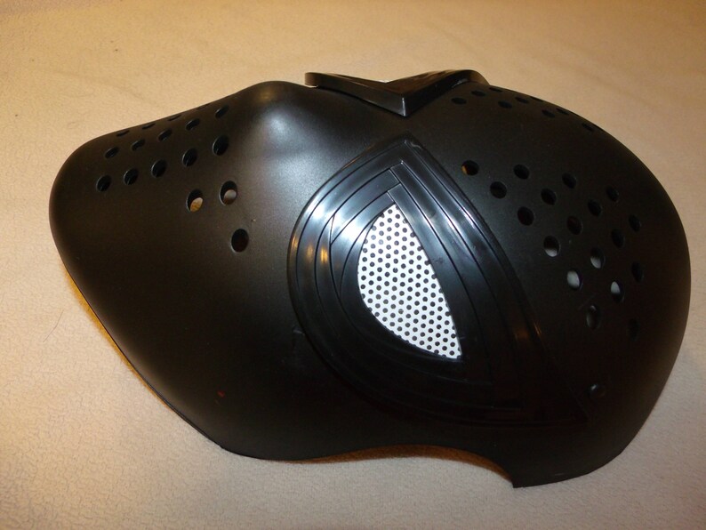 May include: Black plastic mask with a white mesh eye piece and a series of small holes throughout the mask.