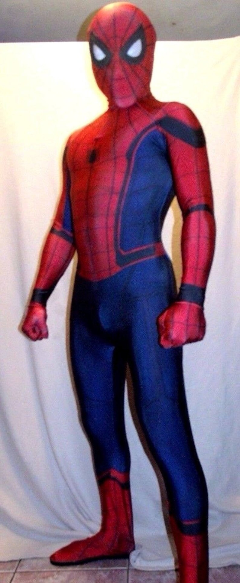 May include: A red and blue spandex costume of Spider-Man with a black spider logo on the chest. The costume has a red mask with black eyes and a black web design.