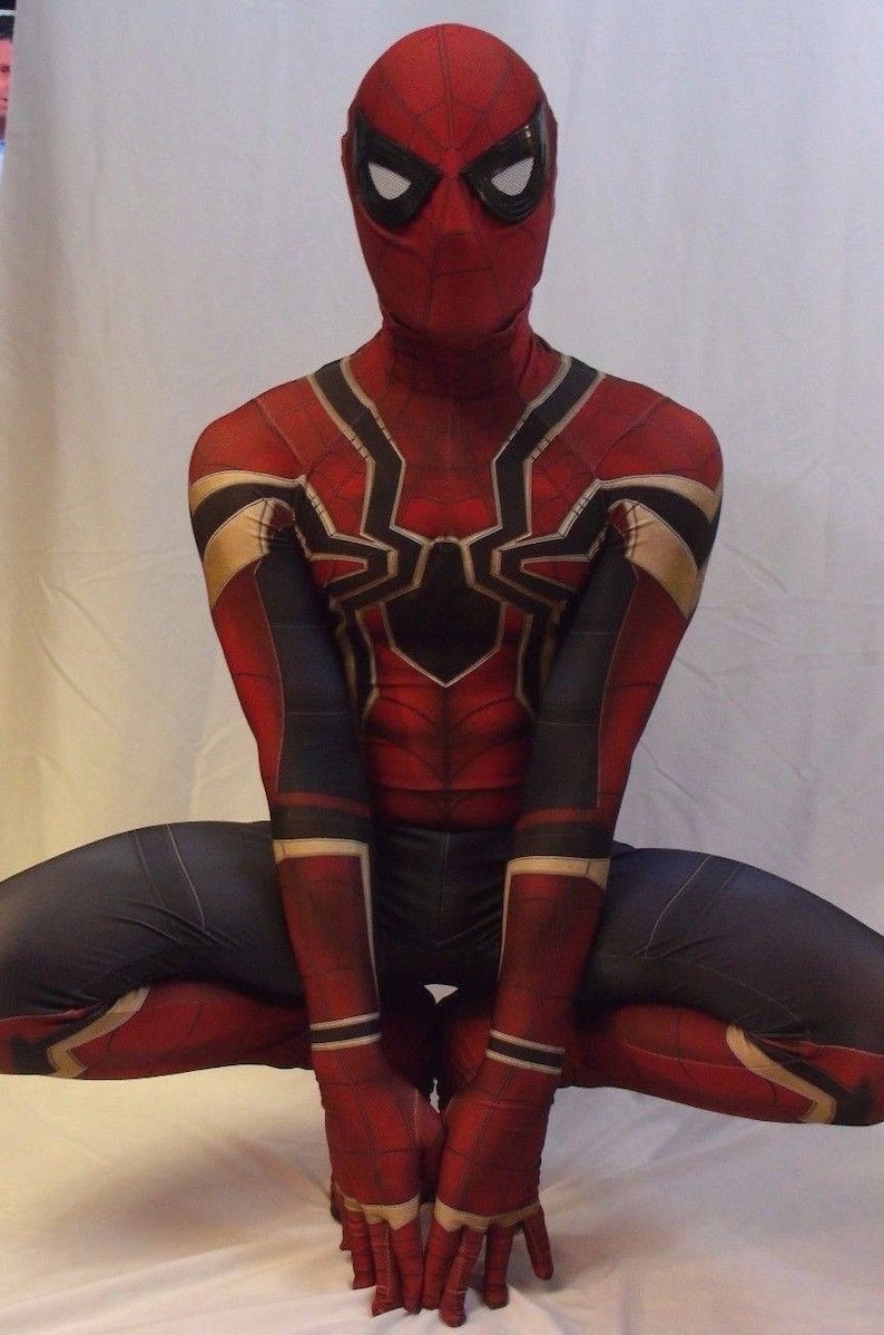 May include: A red and black spandex costume with a spider design. The costume has a red mask with black eyes and a white outline. The figure is in a crouching position with hands clasped in front.