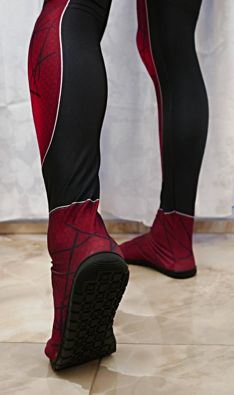 May include: A pair of red and black spandex leggings with a spiderweb pattern. The leggings have a black rubber sole on the bottom.