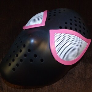 Puede incluir: M&aacute;scara de Spider-Man negra y rosa con un dise&ntilde;o de malla. La m&aacute;scara tiene dos piezas de ojos rosas con un dise&ntilde;o de malla blanca.