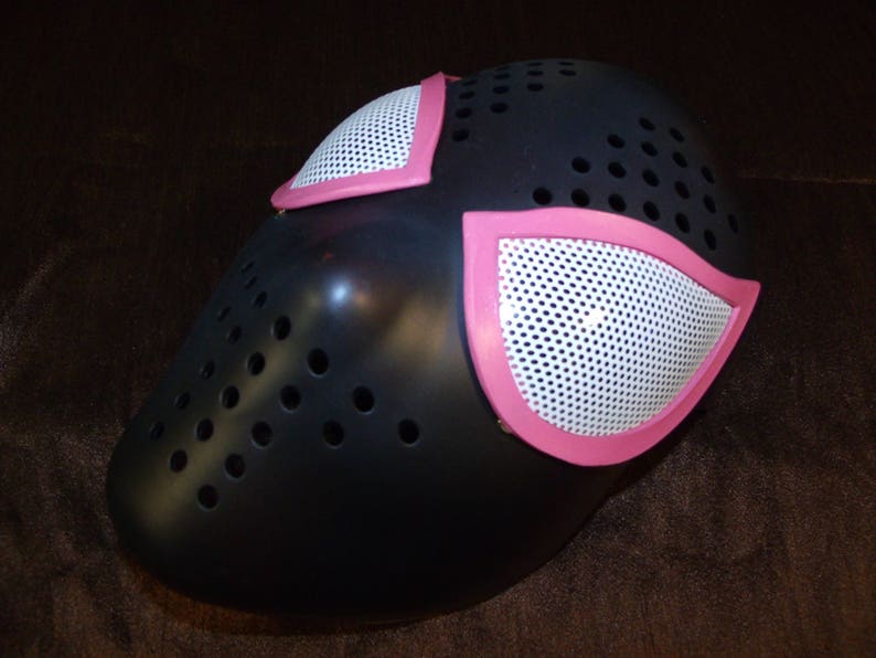 Puede incluir: M&aacute;scara de Spider-Man negra y rosa con un dise&ntilde;o de malla. La m&aacute;scara tiene dos piezas de ojos rosas con un dise&ntilde;o de malla blanca.