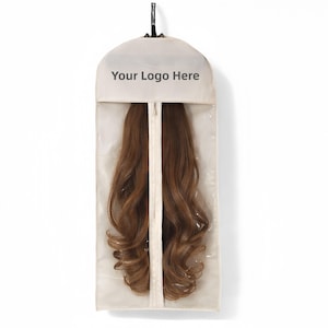 Può includere: Una custodia per abiti beige con pannello frontale in plastica trasparente e cerniera centrale, contenente extension per capelli castani lunghi e mossi. La parte superiore presenta la scritta "Your Logo Here" e un gancio appendiabiti nero.
