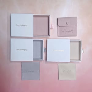 Puede incluir: Cinco cajas y bolsas de joyer&iacute;a diferentes, todas blancas con letras doradas. Las cajas son de TreePackaging y las bolsas son de Howard Jewelry & Design, Liangyu y Fat Zebra.