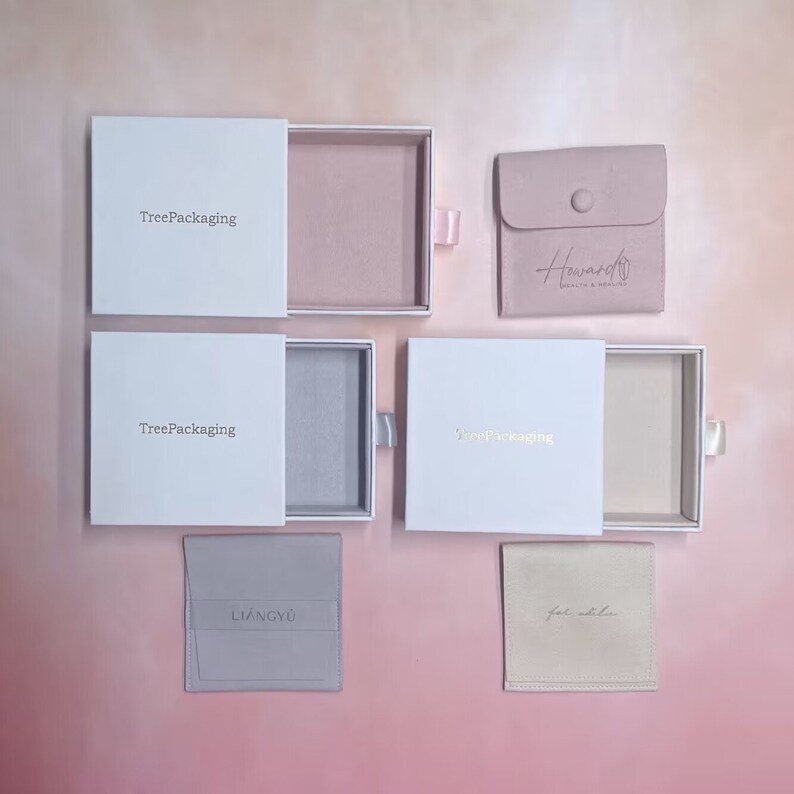 Puede incluir: Cinco cajas y bolsas de joyer&iacute;a diferentes, todas blancas con letras doradas. Las cajas son de TreePackaging y las bolsas son de Howard Jewelry & Design, Liangyu y Fat Zebra.