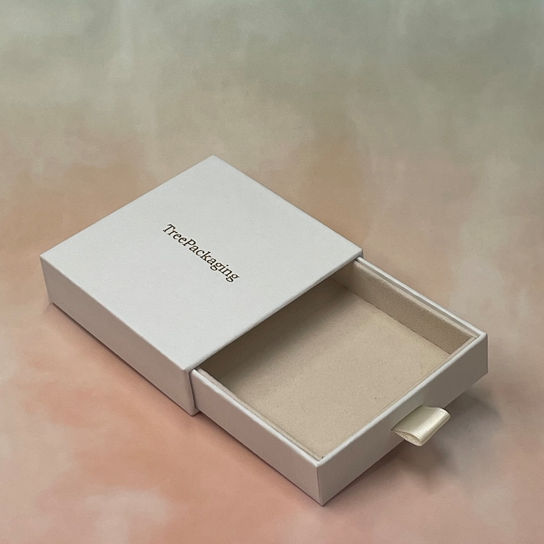 Puede incluir: Caja de caj&oacute;n blanca con una leng&uuml;eta de extracci&oacute;n y el texto "TreePackaging" impreso en la parte superior.
