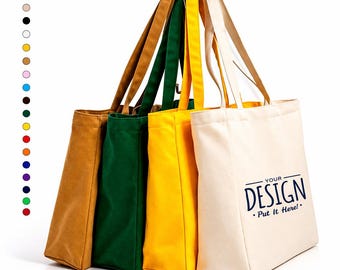 Può includere: Quattro borse tote in tela color marrone chiaro, verde scuro, giallo e bianco sporco, disposte in fila. La borsa color bianco sporco presenta il testo blu scuro "YOUR DESIGN Put It Here!". A sinistra c'è una colonna verticale di sedici piccoli cerchi colorati.