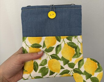 May include: A small blue denim pouch with a yellow button closure. The pouch is lined with a white fabric featuring a lemon print. "INSIDE PATTERN" is written in black text on a white background.