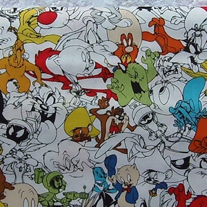 May include: A white fabric with a colorful cartoon print featuring various characters from the Looney Tunes franchise. The characters include Bugs Bunny, Daffy Duck, Tweety Bird, Sylvester the Cat, Porky Pig, and Taz.