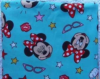 Puede incluir: Tela turquesa con un patrón repetido de Minnie Mouse, estrellas y labios rojos. Minnie Mouse lleva un lazo rojo con lunares blancos.