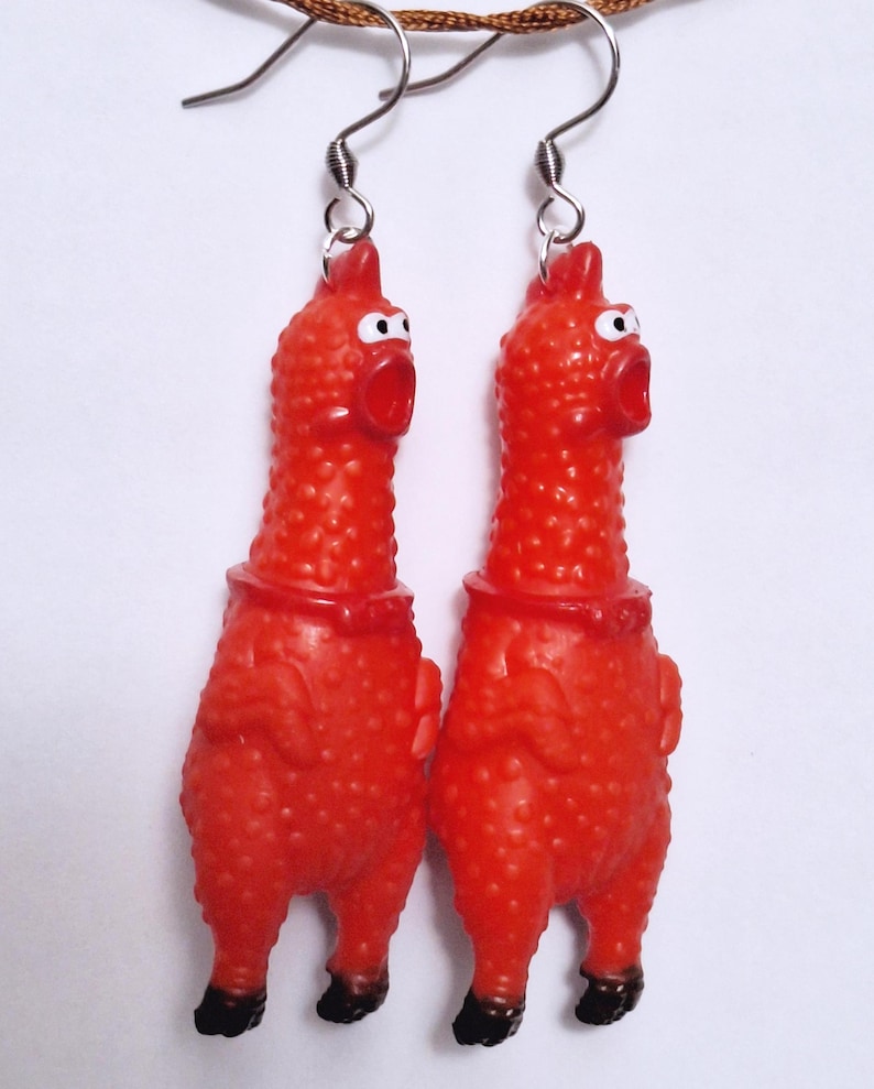 May include: A pair of dangling earrings featuring miniature red rubber chickens with textured skin, wide-open mouths, and white eyes. The chickens have black feet and are attached to silver-toned metal fishhook ear wires for pierced ears.