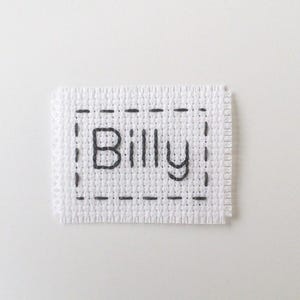 May include: White fabric label with a black stitched border and the name "Billy" embroidered in black thread.