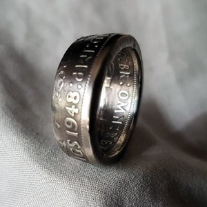 May include: A silver ring made from a 1948 British coin. The ring features the inscription "ONE SHILLING 1948" and the words "BRITISH CROWN" on the side.