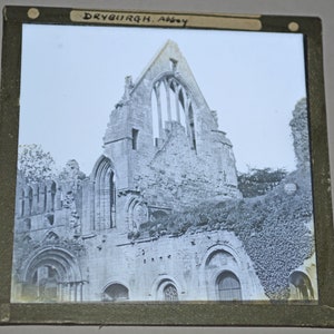 Puede incluir: Fotografía en blanco y negro de las ruinas de la abadía de Dryburgh, un edificio histórico en Escocia. La foto muestra las paredes de piedra y los arcos de la abadía, con hiedra creciendo en las paredes.