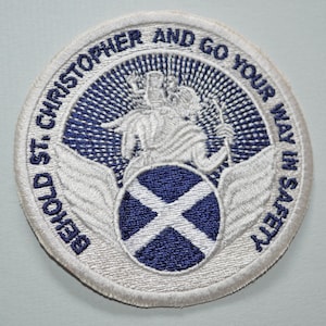 May include: White embroidered patch with a blue and white Scottish flag, a white figure of St. Christopher, and the text "Behold St. Christopher and go your way in safety".