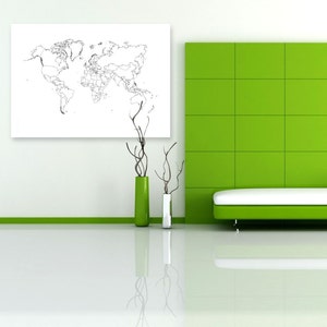 Op de afbeelding: Een witte bank met een wit kussen staat voor een groene betegelde muur. Een witte ingelijste wereldkaart hangt aan de muur achter de bank. Twee vazen met gedroogde takken staan op de vloer voor de bank.