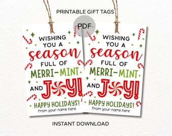 Könnte beinhalten: Zwei bedruckbare Geschenkanhänger mit festlichem Feiertagsdesign. Die Anhänger zeigen den Text "Wishing you a season full of Merri-Mint and Joy!" in Rot und Grün, mit Zuckerstangen- und Pfefferminz-Akzenten. Die Anhänger sind mit Bindfaden aufgereiht.