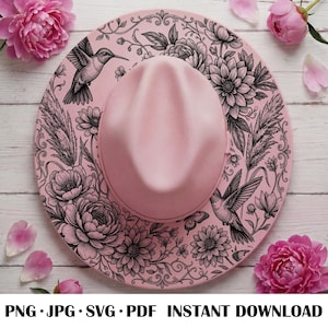 May include: A light pink fedora hat featuring a detailed black line art illustration of hummingbirds, various flowers, and pampas grass across the brim. The design includes intricate floral patterns and scrolling vines surrounding the crown.