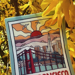 May include: A colorful illustration of the San Francisco skyline with the Golden Gate Bridge in the foreground. The illustration features a sunset with a red sun and yellow, orange, and blue clouds. The text "San Francisco" is at the bottom of the image.