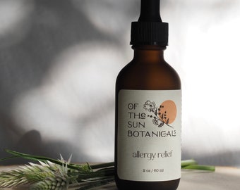 May include: A brown glass bottle with a dropper top, labeled "Of The Sun Botanicals allergy relief 2 oz / 60 ml".