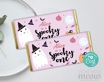 May include: Two pink Halloween-themed chocolate bar wrappers with gold foil edges. Each wrapper features a cartoon ghost wearing a witch hat, pumpkins, bats, and the text "Alice is a spooky one."