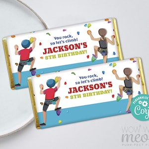 May include: Two personalized chocolate bar wrappers with a blue, white, and yellow climbing wall design. The wrappers feature a cartoon climber and the text "You rock, so let's climb! Jackson's 8th Birthday!"