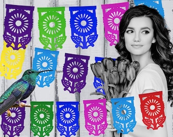 May include: A colorful paper banner with a flower design hangs against a white wood background. A hummingbird sits on a branch in the foreground. A woman holds a bouquet of tulips in front of the banner.