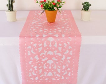 May include: Pink table runner with a delicate floral lace design. The runner is made of felt and has a scalloped edge.