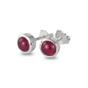 May include: A pair of silver stud earrings with round, red gemstones.
