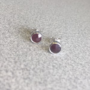 May include: A pair of silver stud earrings with round, dark red gemstones.