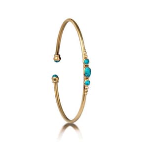 Peut inclure: Un bracelet jonc en or avec des pierres turquoise. Le bracelet a un design simple avec une rangée de pierres turquoise d'un côté.
