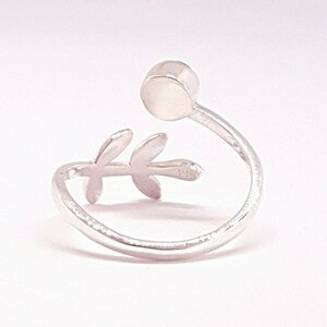 May include: Silver ring with a delicate leaf design and a round, white stone.