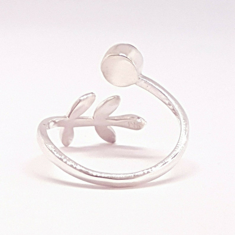 May include: Silver ring with a delicate leaf design and a round, white stone.